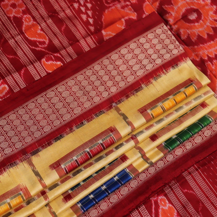 Close-up of multicolored Sambalpuri silk saree fabric texture showing intricate weave and maroon accents.
