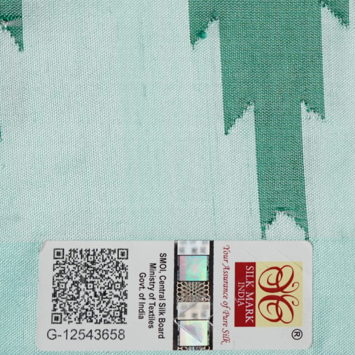 Extreme close-up of the green Sambalpuri silk fabric, revealing its luxurious texture and fine handloom weave.