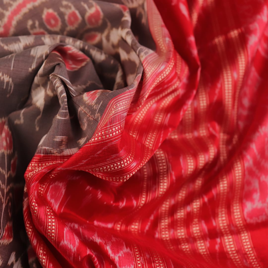 Close-up of grey Sambalpuri silk saree fabric showing intricate motif texture.