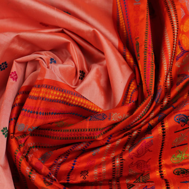 Close-up of finely woven silk fabric featuring intricate Butta patterns in multicolor with an orange accent