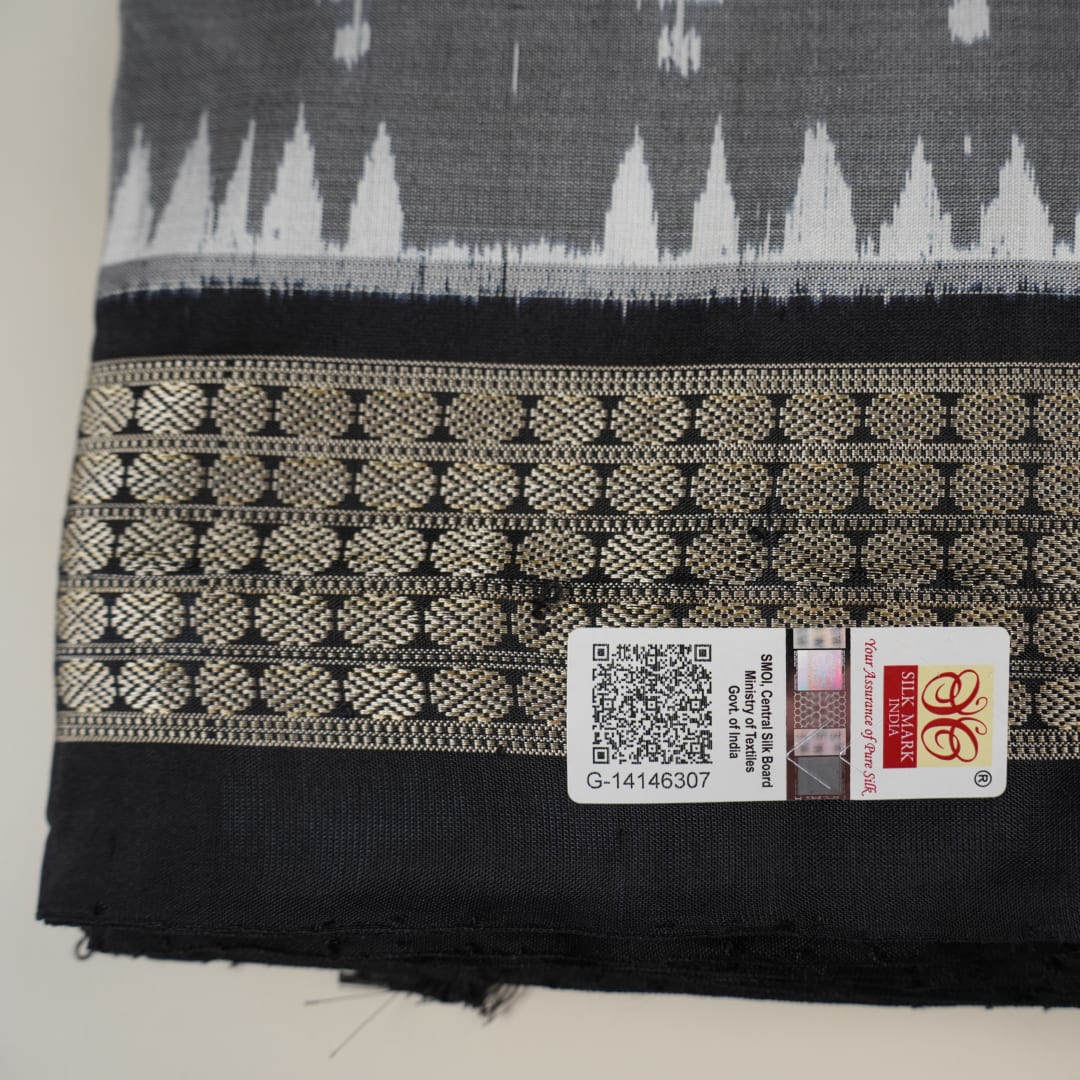 Close-up of grey & black Sambalpuri silk saree fabric, highlighting its rich texture and weave.