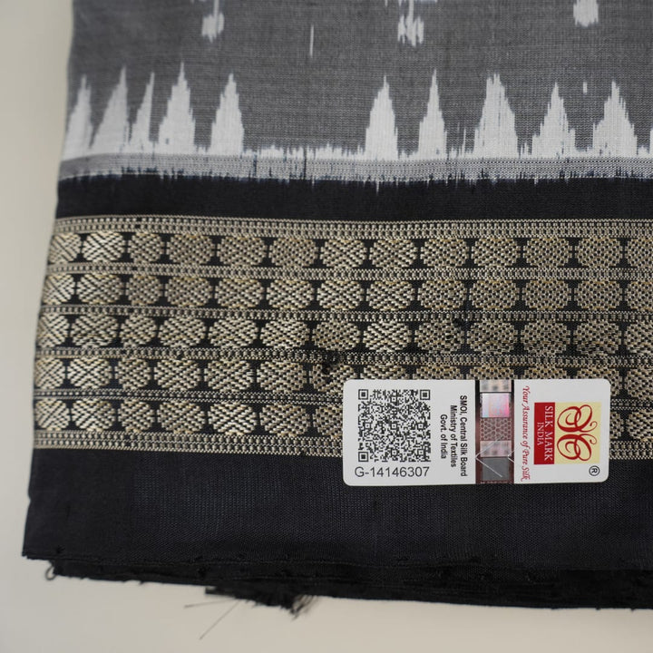 Close-up of grey & black Sambalpuri silk saree fabric, highlighting its rich texture and weave.