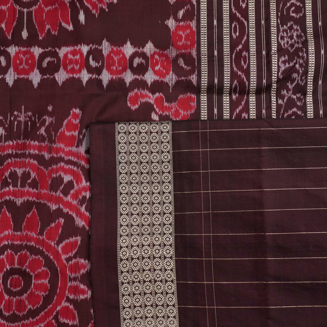 Ultra close-up of the red Sambalpuri silk saree fabric, revealing its luxurious texture and handloom weave.