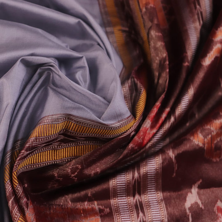 Close-up of grey and maroon Sambalpuri Silk Saree's butta pattern fabric texture.