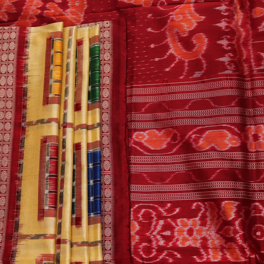 Close-up of multicolored Sambalpuri silk saree fabric texture showing intricate weave and maroon accents.