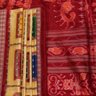 Close-up of multicolored Sambalpuri silk saree fabric texture showing intricate weave and maroon accents.