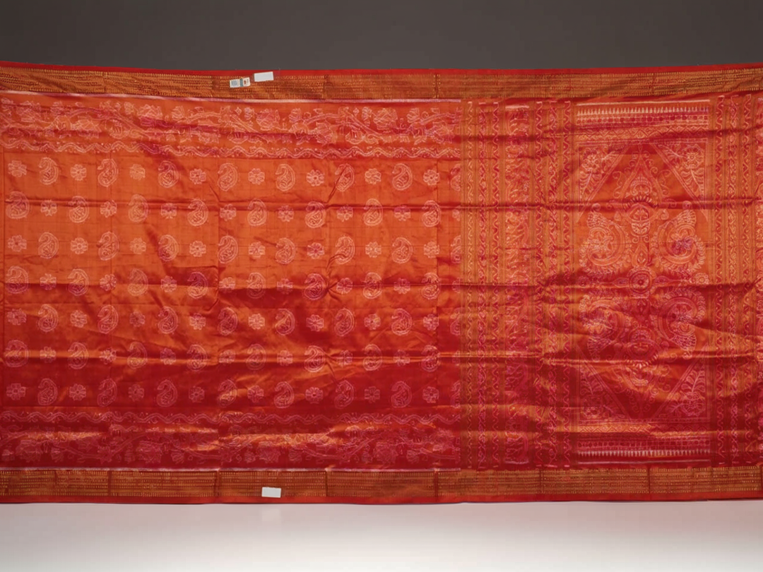 Close-up of rust Sambalpuri silk fabric, revealing its luxurious texture and fine handloom weave.