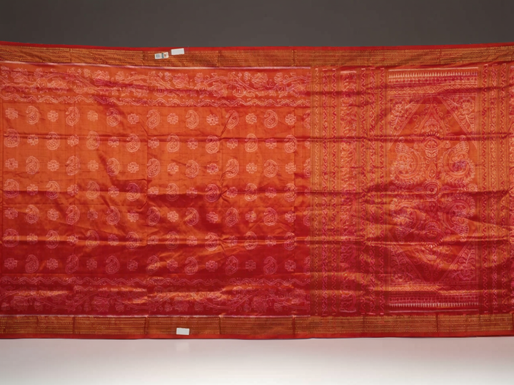 Close-up of rust Sambalpuri silk fabric, revealing its luxurious texture and fine handloom weave.