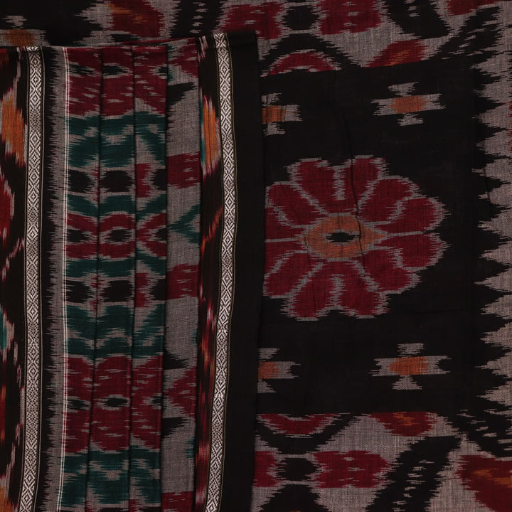 A woman draped in a grey and black cotton Sambalpuri saree, showcasing intricate motifs on the pallu and body.