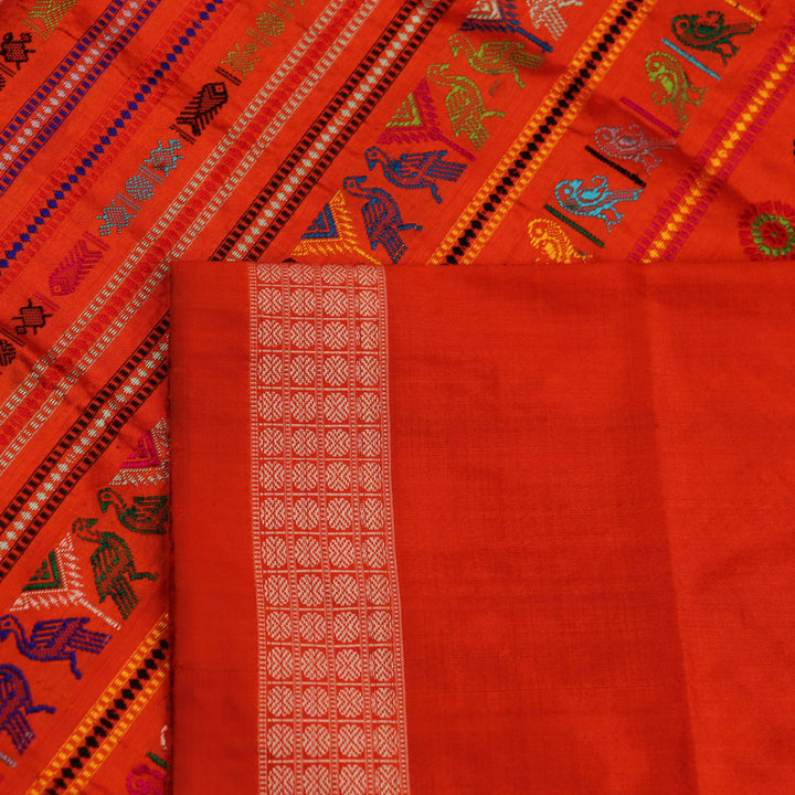 Close-up of finely woven silk fabric featuring intricate Butta patterns in multicolor with an orange accent