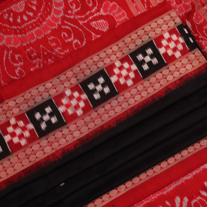 Close-up of black and red silk saree fabric with intricate Sambalpuri motifs