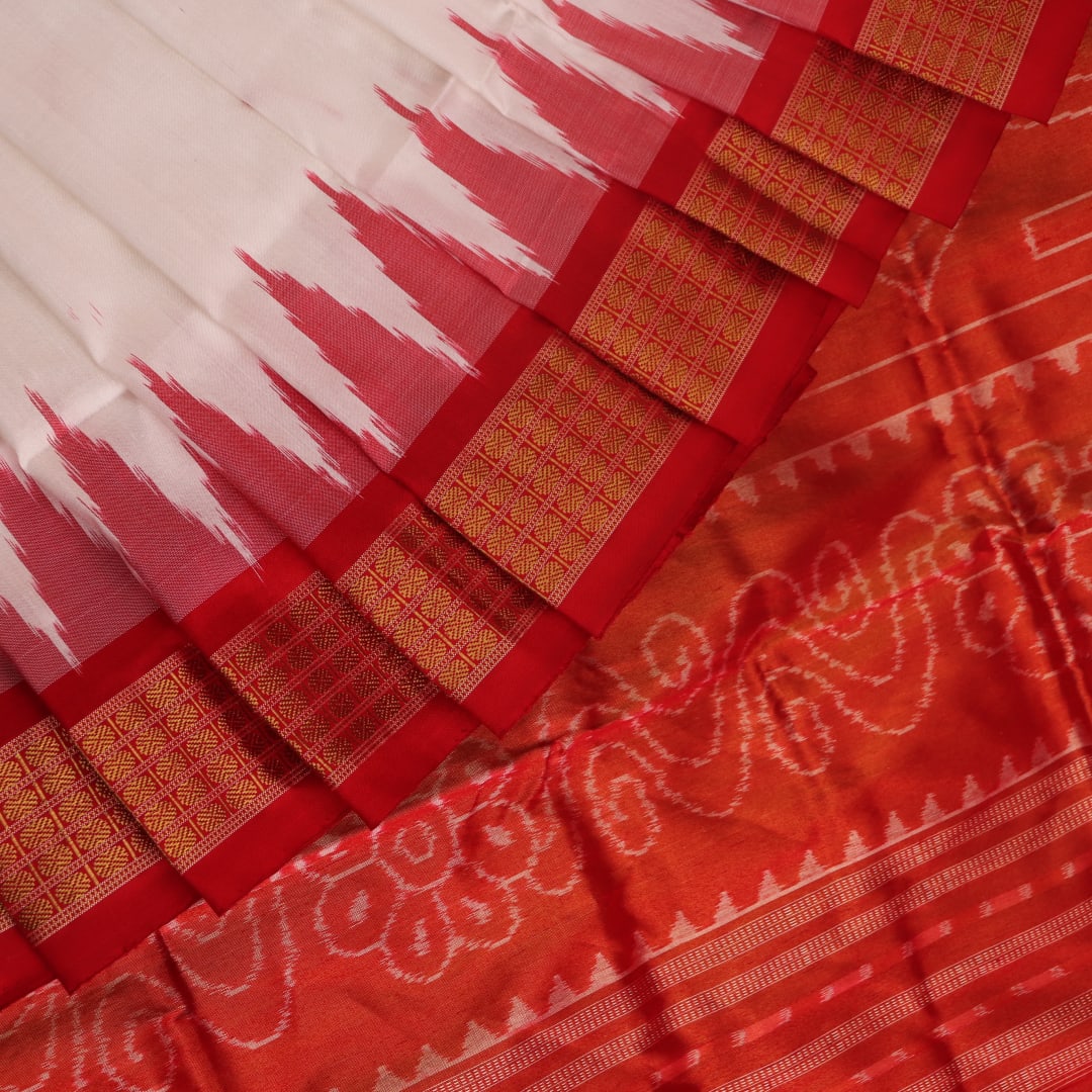 Close-up of white and red silk Bomkai saree fabric texture with butta pattern.