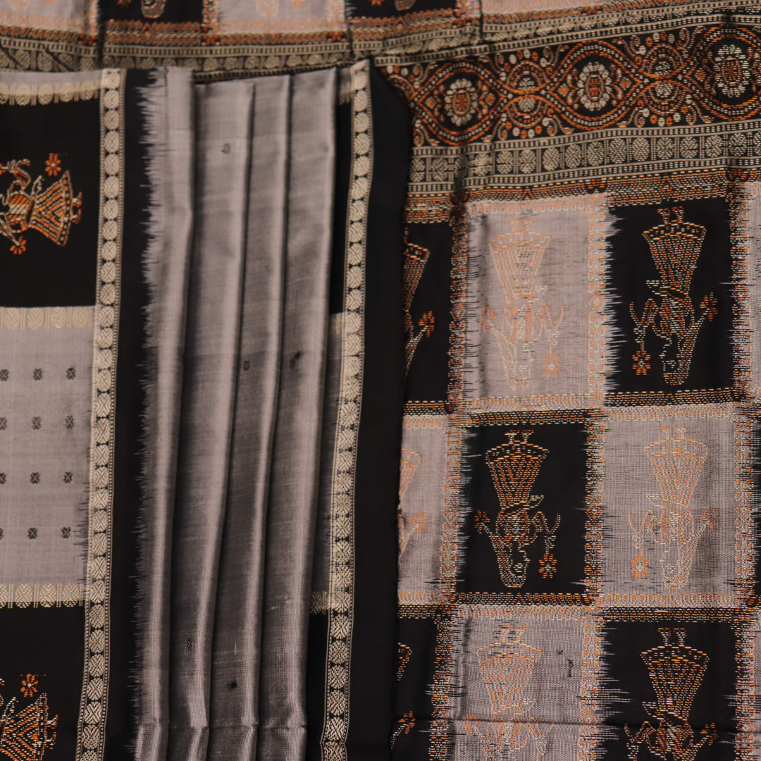 Close-up of intricate silk fabric texture in grey and black, featuring a traditional Bomkai butta pattern