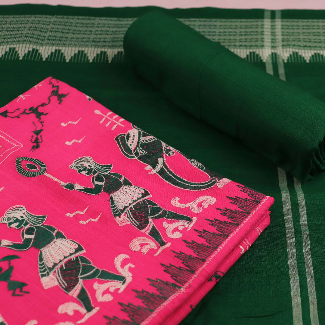 Close-up of the green and pink fabric texture of a Sambalpuri cotton dress material, featuring a repeating doll pattern.