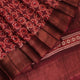 Close-up of maroon Tussar silk saree fabric, revealing its characteristic slub texture and printed details.