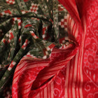 Close-up of green Sambalpuri silk saree fabric showing intricate woven motif texture and red thread details.