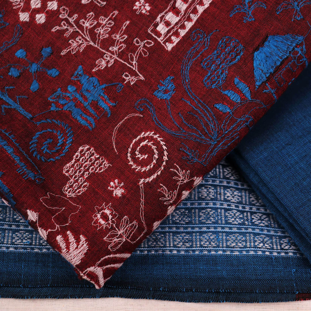 Close-up view of maroon and blue cotton Sambalpuri dress material, showcasing intricate doll pattern.