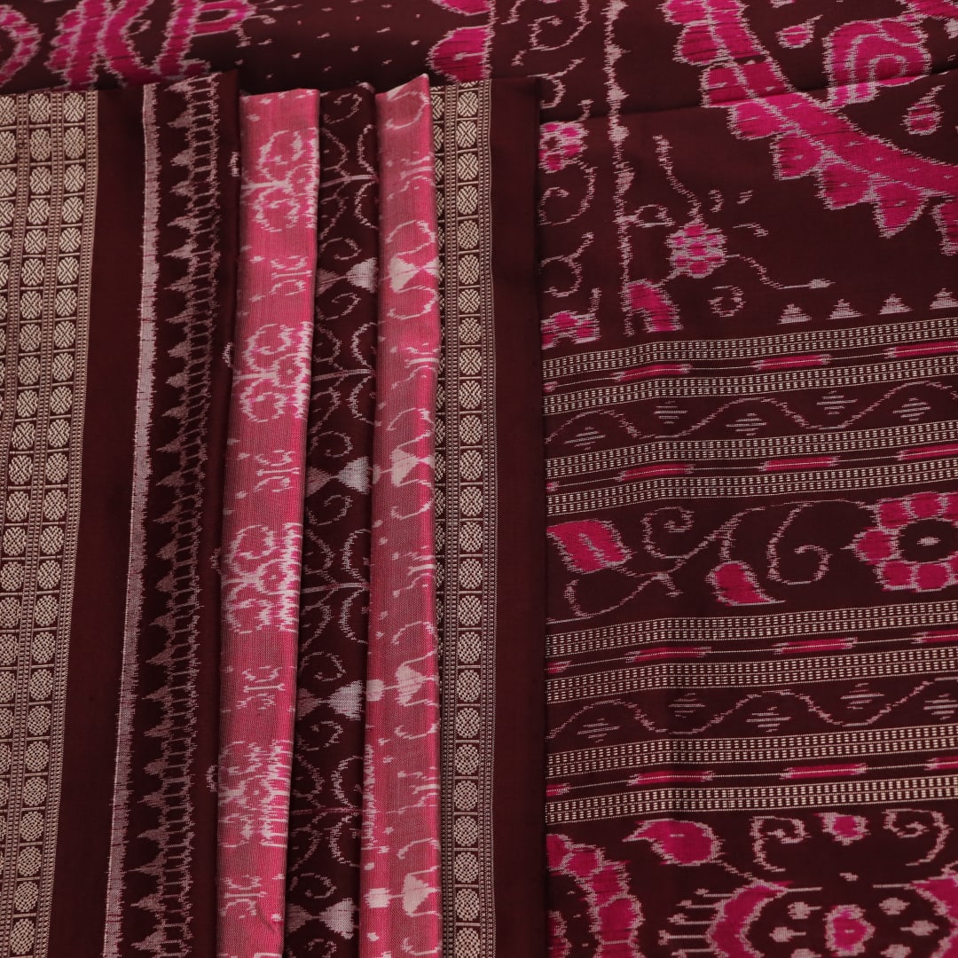 Close-up of peach and maroon Sambalpuri silk saree fabric showing intricate handloom texture and motifs.