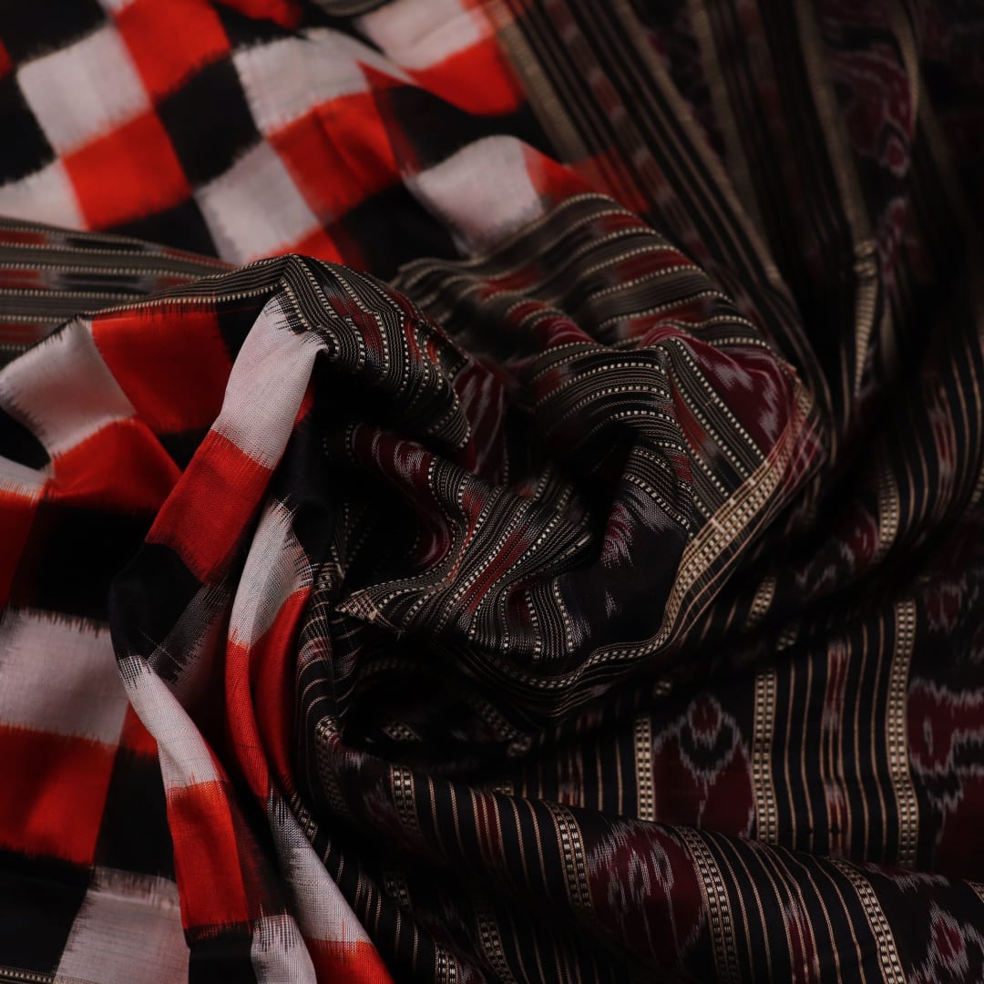 Close-up view of the smooth, lustrous texture of black silk fabric with a Pasapalli pattern in the Sambalpuri style