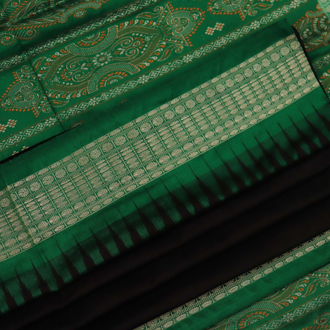 Close-up view of black silk Bomkai saree, showcasing intricate butta patterns and green accents