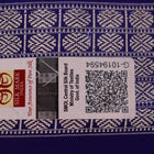 Close-up of red Sambalpuri silk saree fabric showing intricate woven motif texture and subtle blue threads.