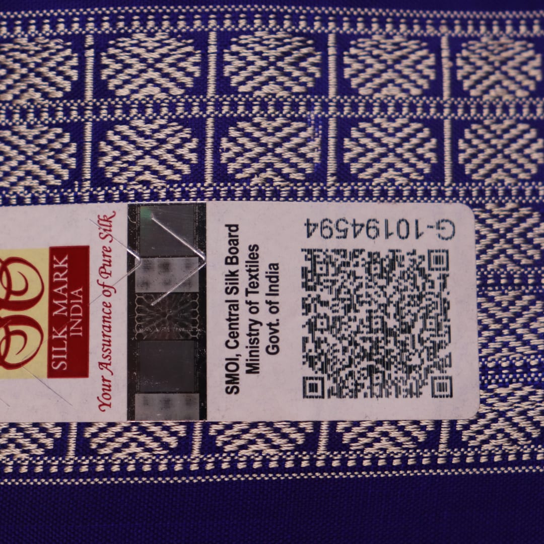 Close-up of red Sambalpuri silk saree fabric showing intricate woven motif texture and subtle blue threads.