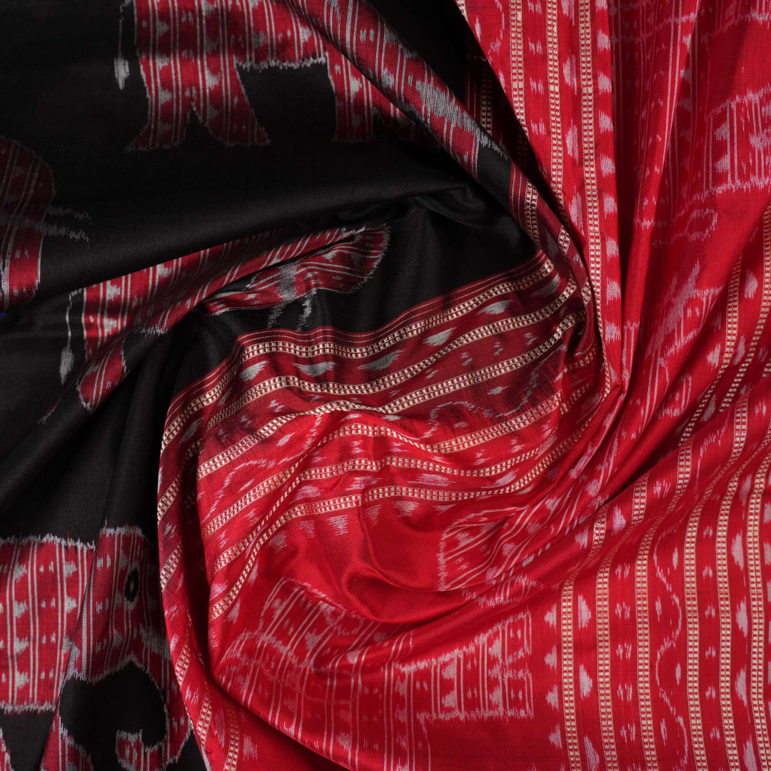Close-up showing the luxurious texture and fine weave of the black Sambalpuri silk fabric.
