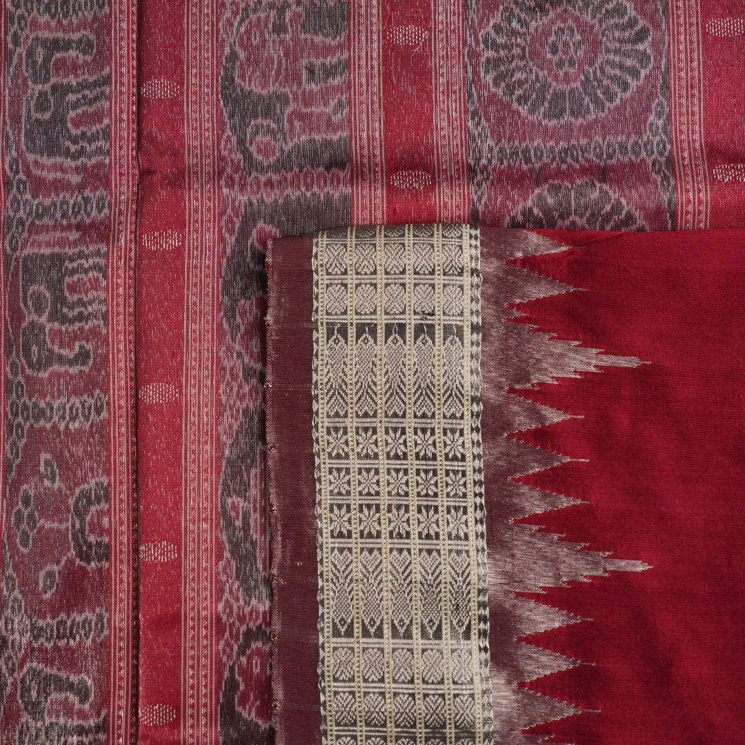 Extreme close-up revealing the rich texture and intricate handloom weave of the maroon and grey Sambalpuri silk fabric.