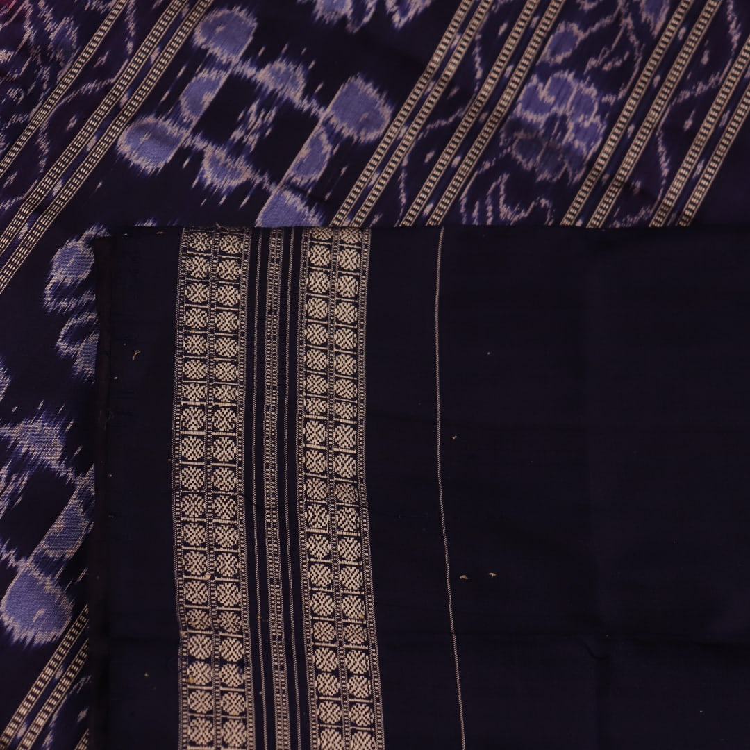 Close-up showing the intricate silk fabric texture of a magenta Sambalpuri saree with multicolor motifs.