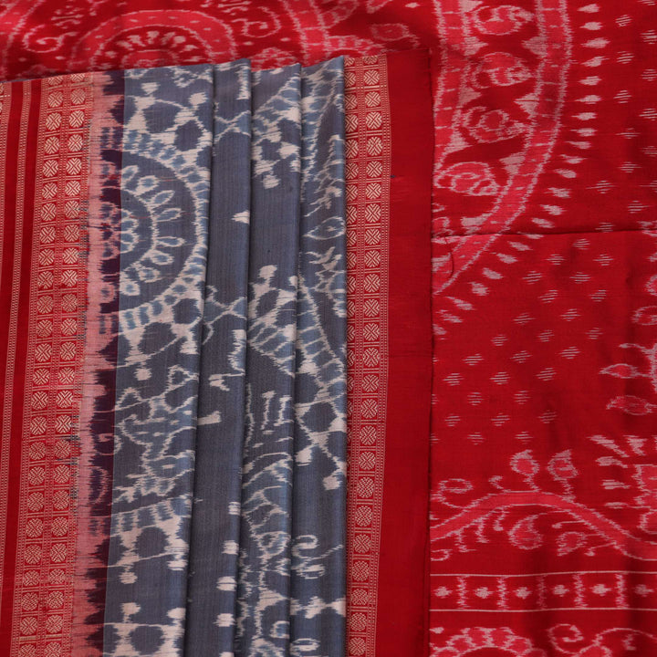 Close-up of grey and red Sambalpuri silk saree fabric showing intricate woven motif texture.