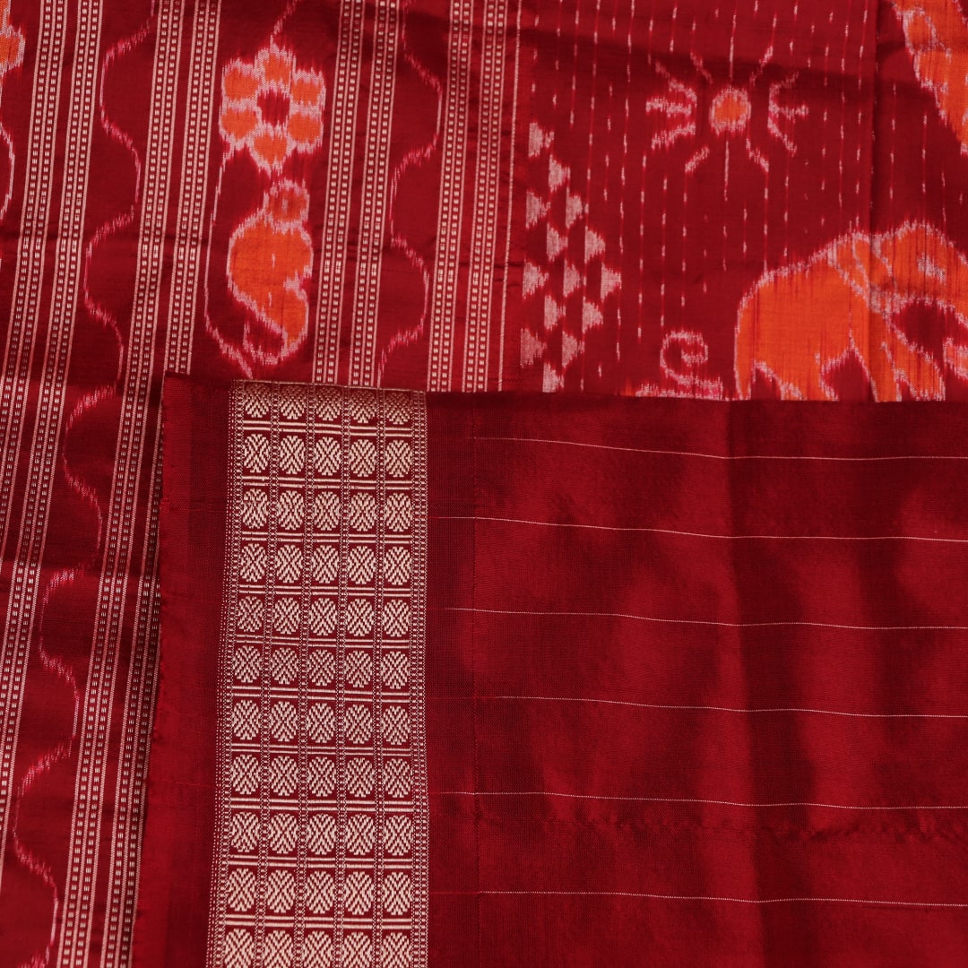 Close-up of multicolored Sambalpuri silk saree fabric texture showing intricate weave and maroon accents.