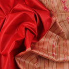 Close-up of plain red and off-white Tussar silk saree fabric texture.