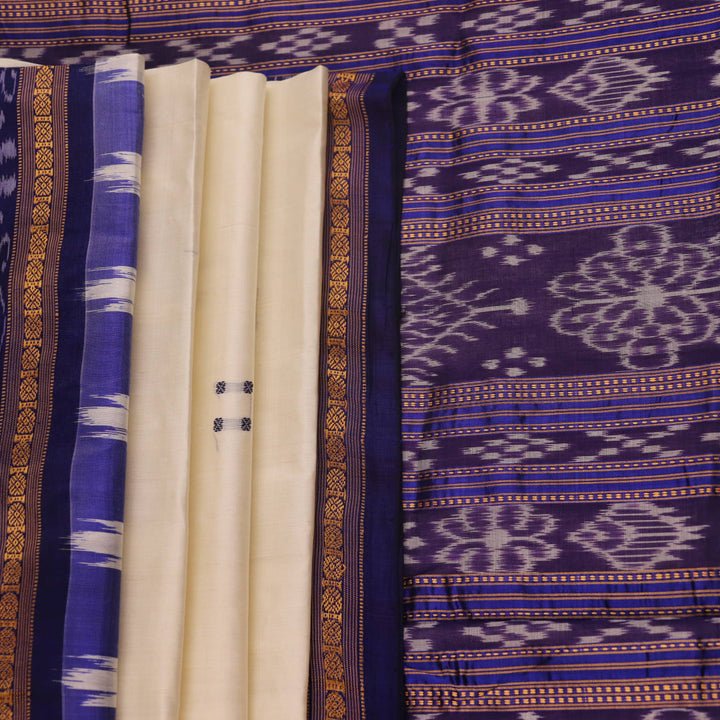 Woman elegantly draped in a white and blue Khandua silk saree with butta pattern.