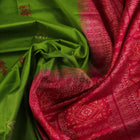 Textured close-up of green Bomkai silk saree fabric, revealing intricate weave and magenta butta pattern.