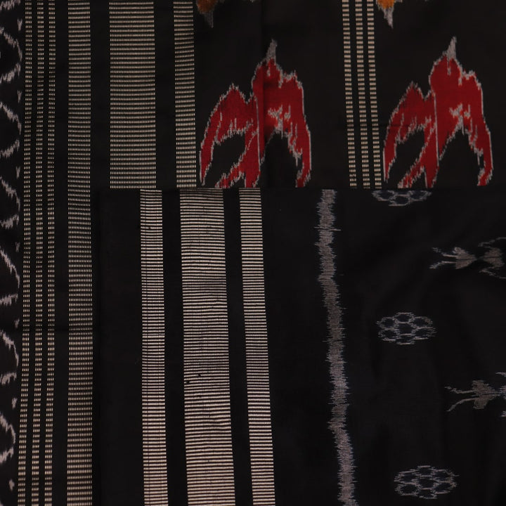 Close-up of the textured silk fabric of a black Sambalpuri saree showing intricate motifs.