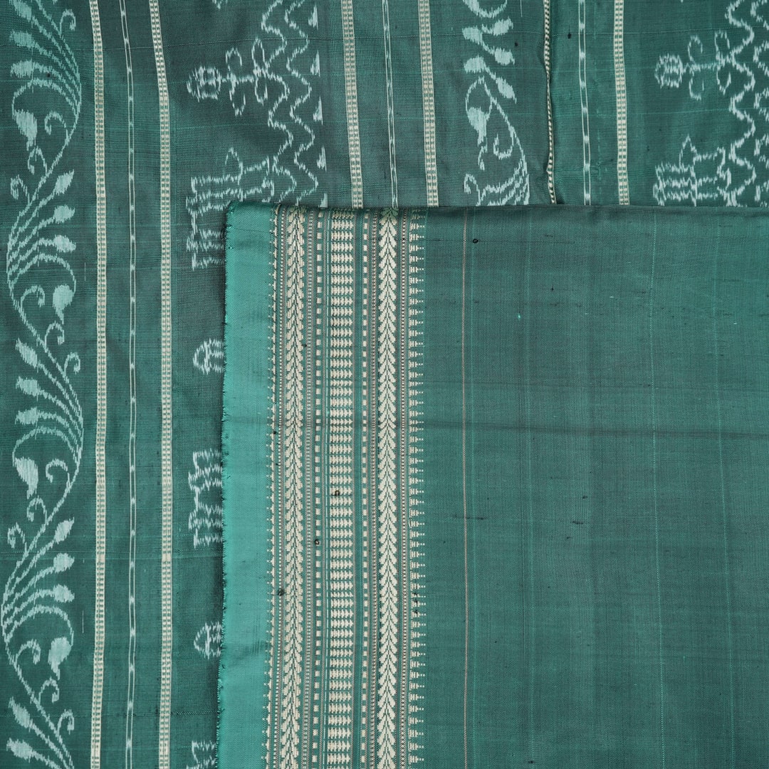 Close-up of green Sambalpuri silk fabric, showing its luxurious texture and fine handloom weave.