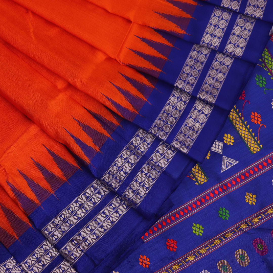 Close-up view of the vibrant orange and blue silk fabric texture with intricate butta pattern