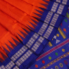 Close-up view of the vibrant orange and blue silk fabric texture with intricate butta pattern
