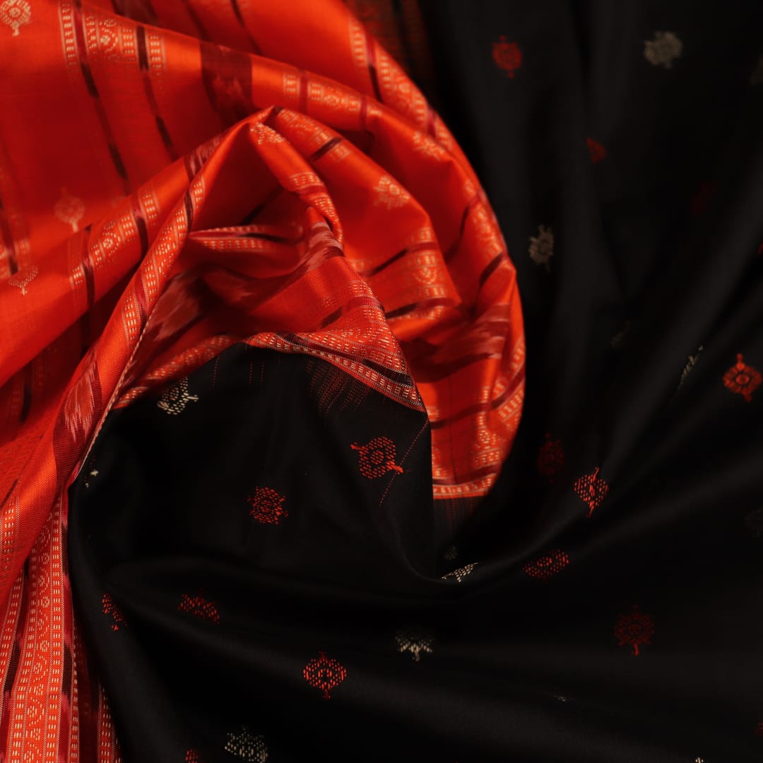 Close-up view of black silk Bomkai saree fabric showcasing its intricate butta pattern.