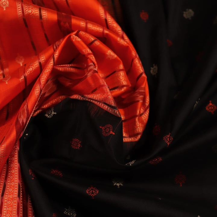 Close-up view of black silk Bomkai saree fabric showcasing its intricate butta pattern.