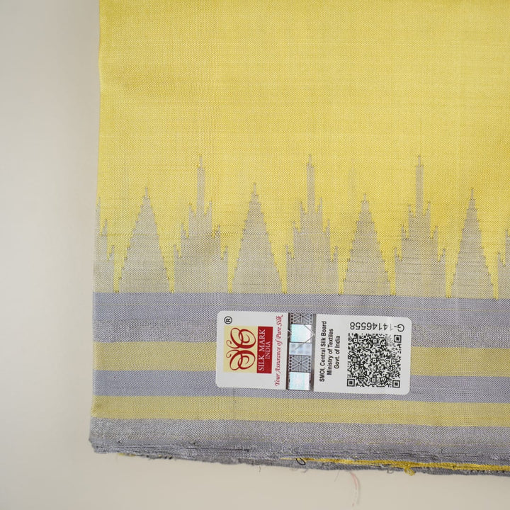 Close-up of the luxurious yellow Sambalpuri silk fabric, showing its fine weave and texture.