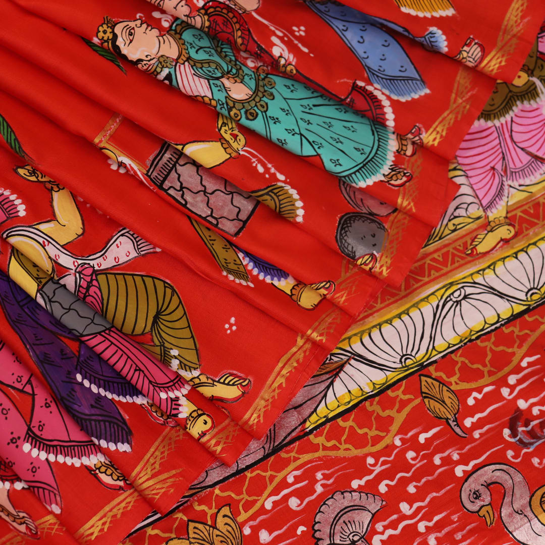 Close-up of red Patachitra silk saree fabric showing hand-painted texture.