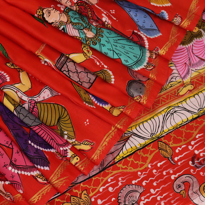 Close-up of red Patachitra silk saree fabric showing hand-painted texture.
