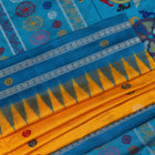 Close-up of the yellow Bomkai silk saree fabric texture, revealing its intricate weave and butta pattern.