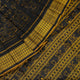 Close-up of the black Sambalpuri silk saree fabric, revealing its rich texture and the intricate weave of the motifs.