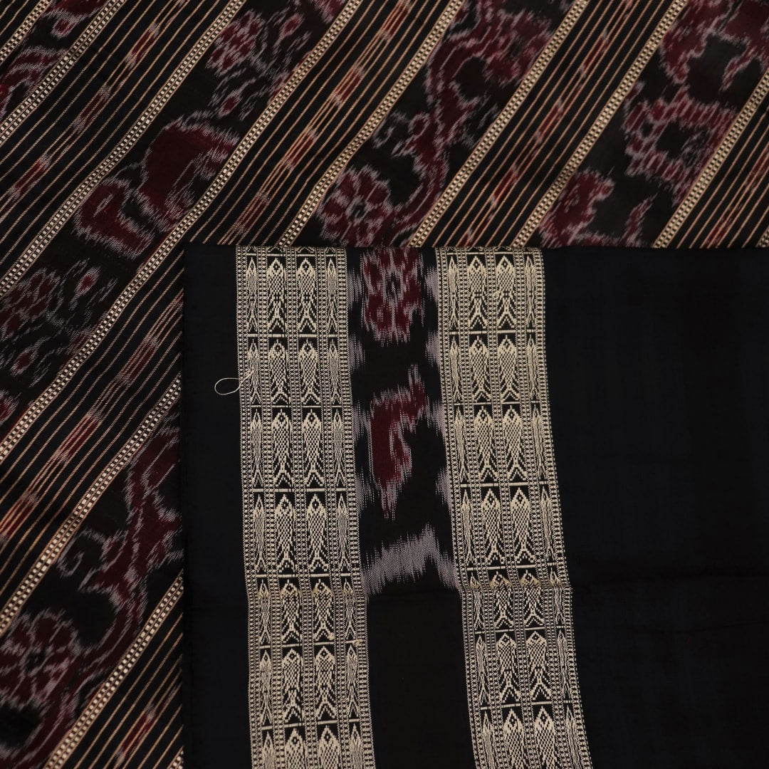 Close-up view of the smooth, lustrous texture of black silk fabric with a Pasapalli pattern in the Sambalpuri style