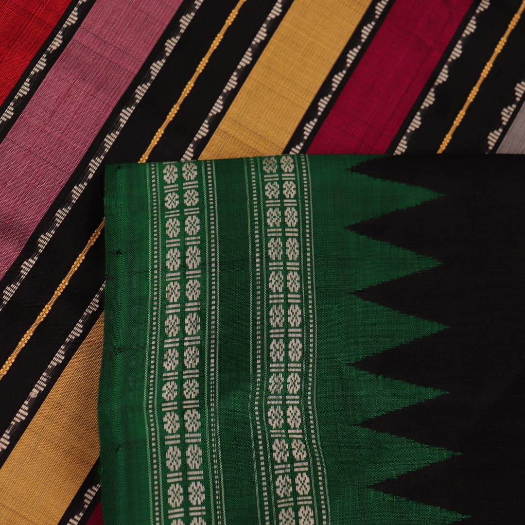 A close-up view of the lush, green silk fabric with a black butta pattern woven in.