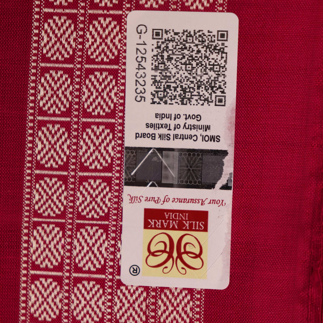 Textured close-up of green Bomkai silk saree fabric, revealing intricate weave and magenta butta pattern.