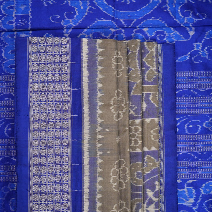 Extreme close-up of the grey and blue Sambalpuri silk saree fabric, revealing its rich texture and intricate weave.
