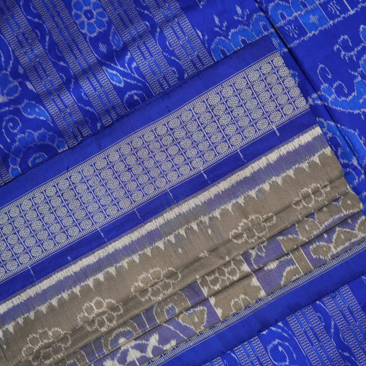 Extreme close-up of the grey and blue Sambalpuri silk saree fabric, revealing its rich texture and intricate weave.